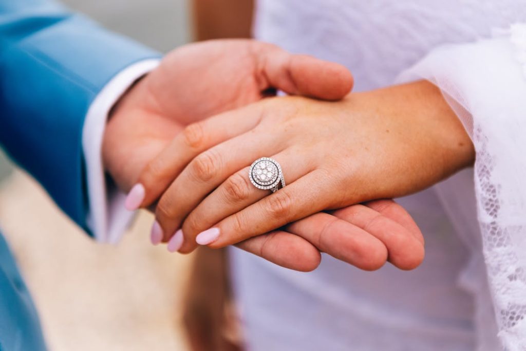 a groom holding the hand of his bride wearing a ring